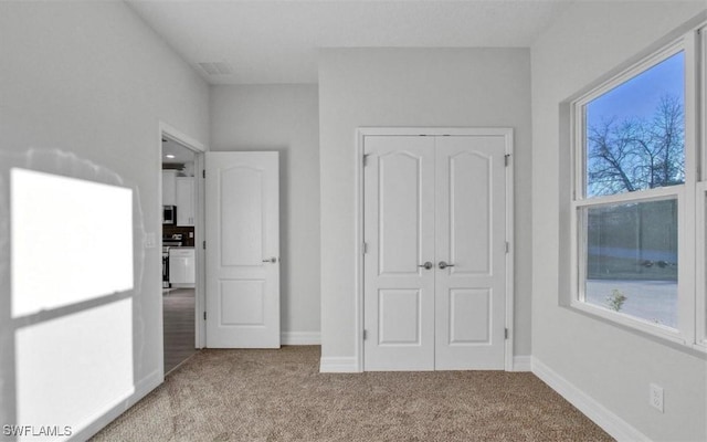 unfurnished bedroom with a closet, light colored carpet, and multiple windows