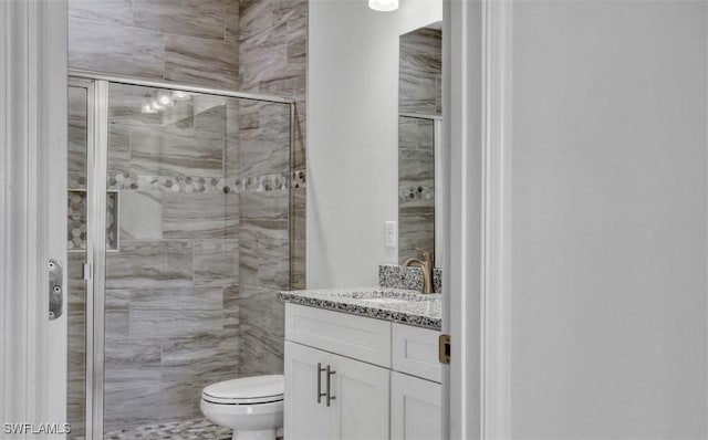 bathroom featuring vanity, a shower with shower door, and toilet