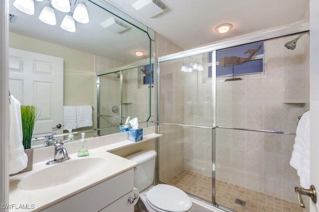 bathroom featuring toilet, vanity, a shower stall, and visible vents