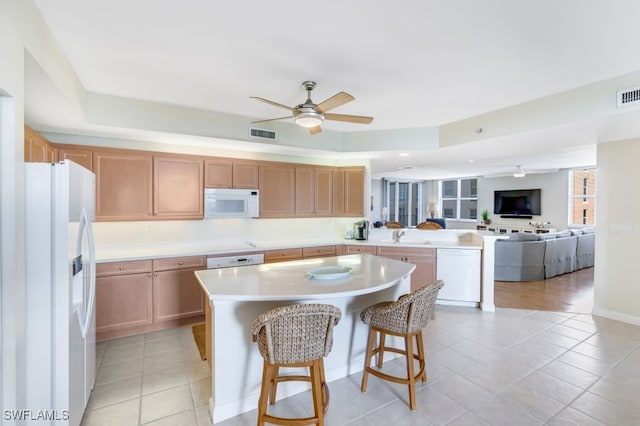 kitchen with a center island, a kitchen bar, white appliances, and light tile patterned floors