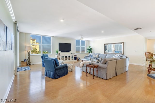 living room featuring a wealth of natural light, crown molding, and light hardwood / wood-style flooring