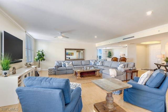 living room with ceiling fan, ornamental molding, and light wood-type flooring