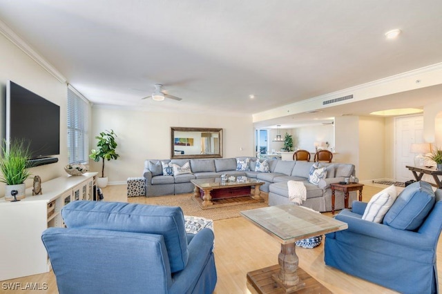 living room featuring baseboards, visible vents, a ceiling fan, light wood-style flooring, and ornamental molding