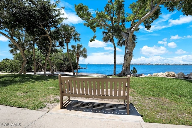 view of home's community with a water view and a lawn