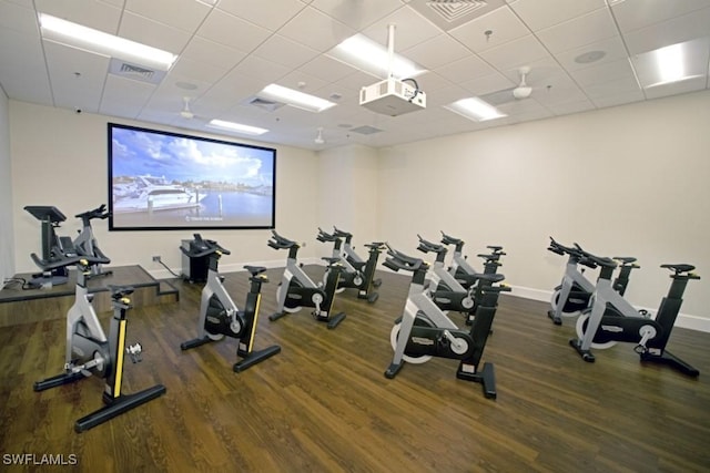 exercise room featuring a paneled ceiling, baseboards, visible vents, and wood finished floors