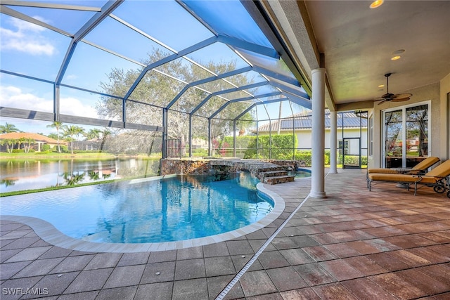 view of swimming pool featuring a hot tub, a patio area, a lanai, ceiling fan, and a water view