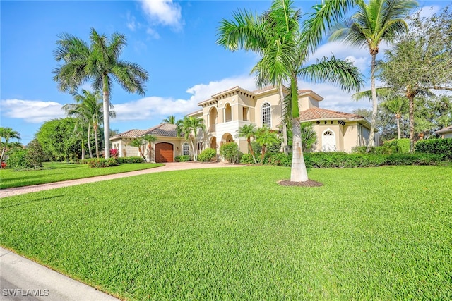 mediterranean / spanish-style home featuring a front lawn and a garage