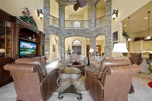 living room featuring a towering ceiling, ceiling fan, and light tile patterned floors