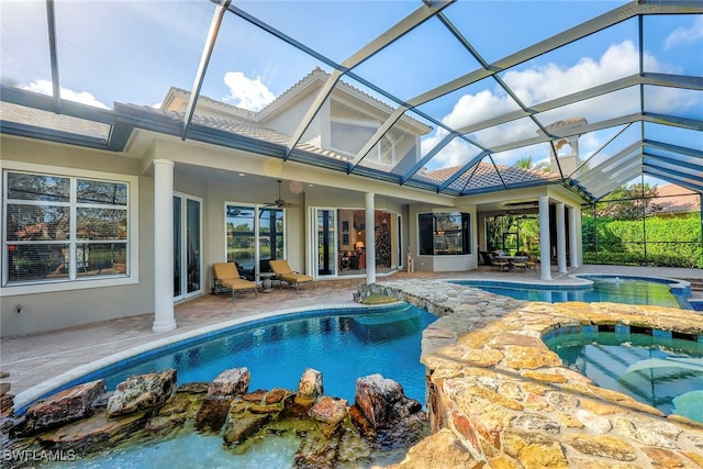 view of pool with an in ground hot tub, ceiling fan, glass enclosure, and a patio