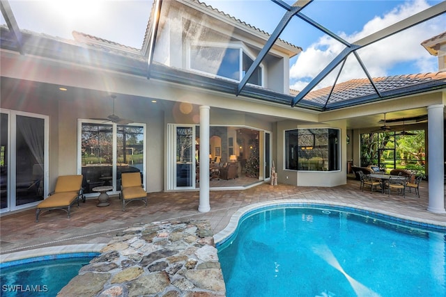 view of pool with a patio, ceiling fan, and glass enclosure