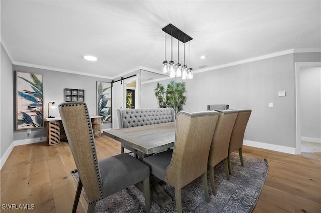 dining space featuring a barn door, crown molding, and hardwood / wood-style flooring