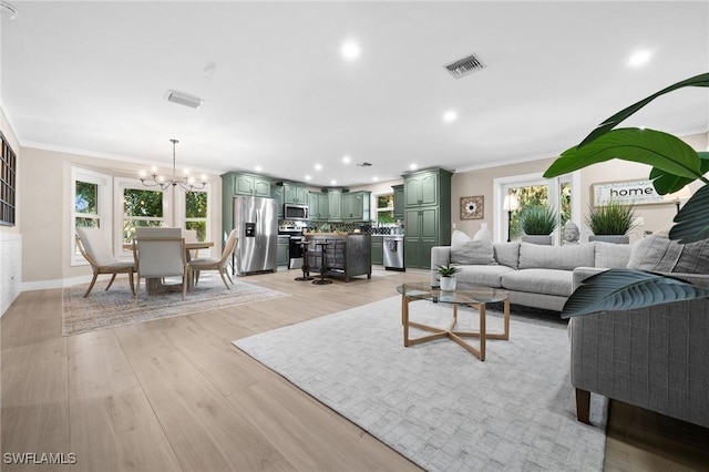 living room with light hardwood / wood-style floors, a chandelier, a healthy amount of sunlight, and ornamental molding