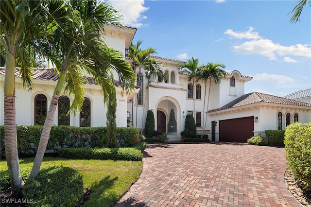 mediterranean / spanish house with a front yard and a garage