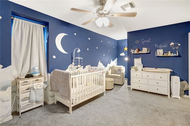 bedroom with ceiling fan, carpet flooring, and a crib