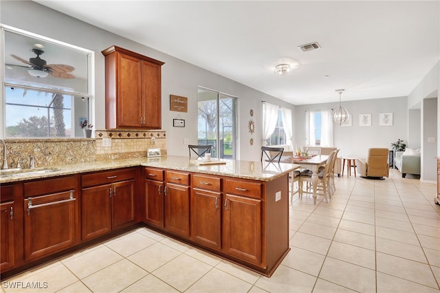 kitchen featuring kitchen peninsula, light tile patterned floors, backsplash, pendant lighting, and sink