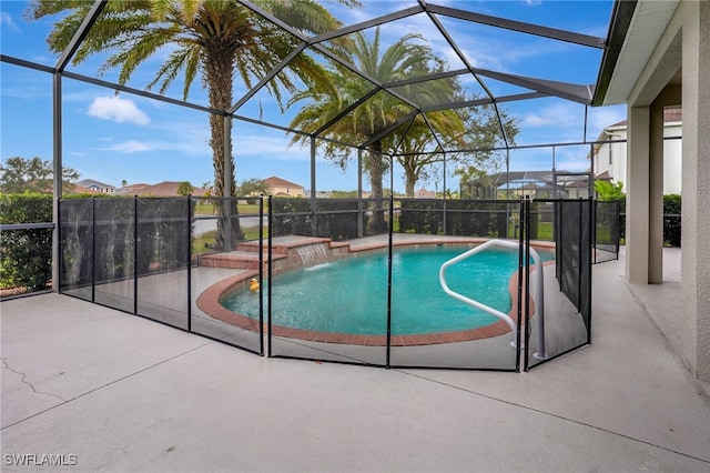 view of pool with a patio, pool water feature, and glass enclosure