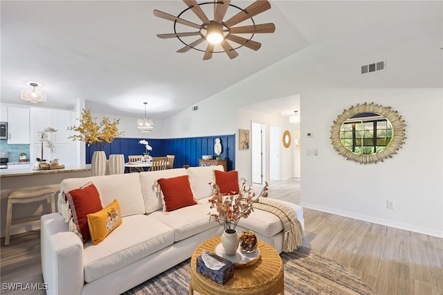 living room featuring vaulted ceiling, light hardwood / wood-style floors, and ceiling fan