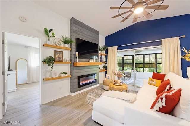 living room featuring a large fireplace, lofted ceiling, light wood-type flooring, and ceiling fan