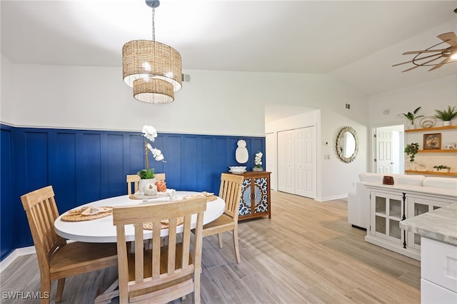 dining space with light hardwood / wood-style flooring, lofted ceiling, and ceiling fan with notable chandelier