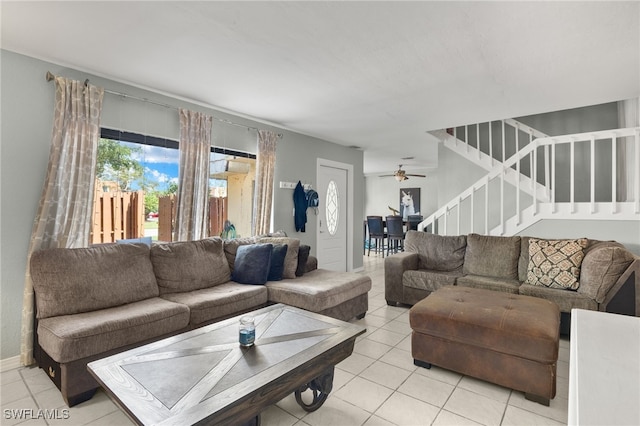 living room featuring stairway, light tile patterned flooring, and a ceiling fan