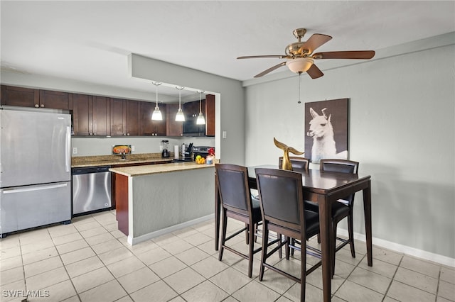 kitchen featuring baseboards, a peninsula, light countertops, dark brown cabinets, and appliances with stainless steel finishes