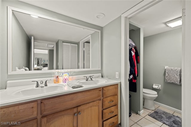 bathroom with a closet, tile patterned flooring, double vanity, and a sink