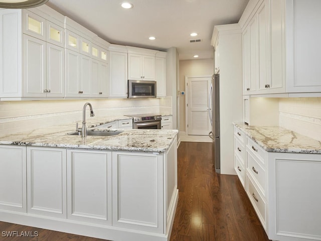 kitchen featuring appliances with stainless steel finishes, sink, dark hardwood / wood-style flooring, white cabinets, and light stone counters