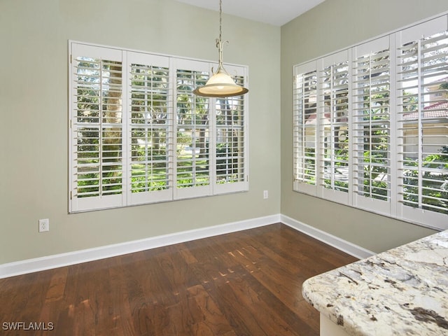 unfurnished dining area featuring a healthy amount of sunlight and dark hardwood / wood-style flooring