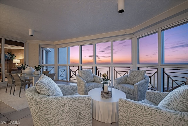 tiled living room featuring a textured ceiling and a water view