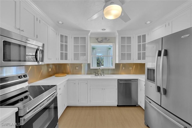 kitchen featuring tasteful backsplash, white cabinetry, sink, light hardwood / wood-style floors, and stainless steel appliances