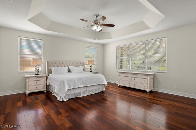 bedroom featuring a raised ceiling, ceiling fan, and dark hardwood / wood-style flooring