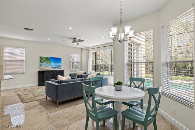 dining space featuring ceiling fan with notable chandelier