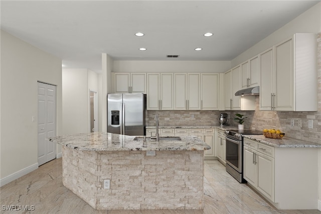 kitchen with an island with sink, stainless steel appliances, light stone counters, and sink