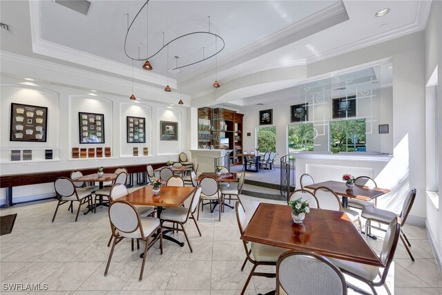 tiled dining space with a raised ceiling and crown molding