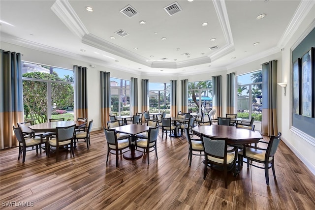 dining room with dark wood-type flooring, crown molding, and a tray ceiling