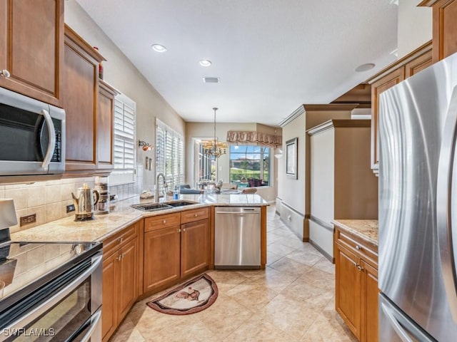 kitchen with appliances with stainless steel finishes, pendant lighting, tasteful backsplash, sink, and light stone countertops