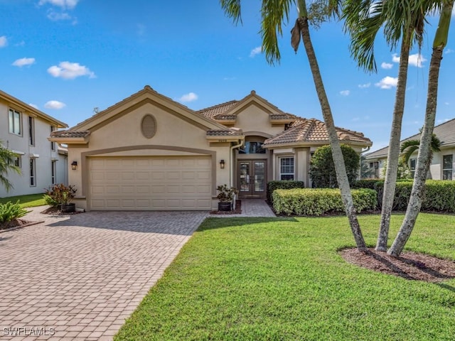 mediterranean / spanish-style home featuring french doors, a garage, and a front lawn