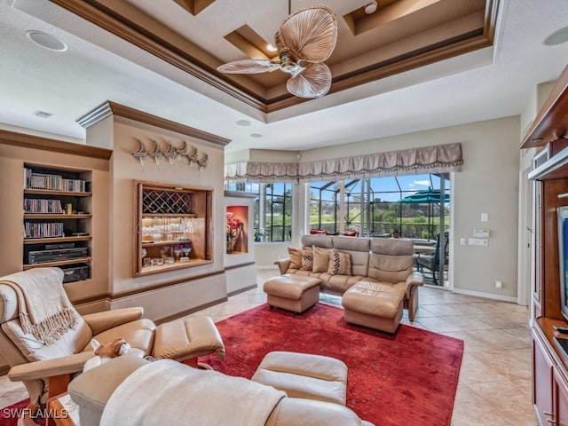 tiled living room with a raised ceiling, ceiling fan, and ornamental molding