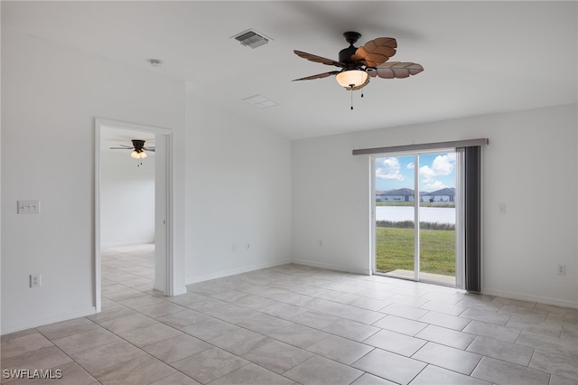 empty room with light tile patterned flooring, a water view, and ceiling fan