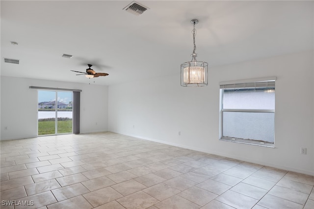 spare room with a water view, light tile patterned floors, and ceiling fan with notable chandelier