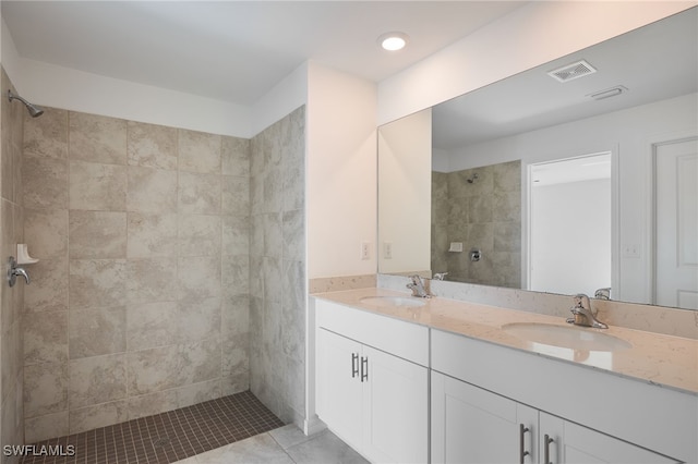 bathroom with vanity, a tile shower, and tile patterned flooring