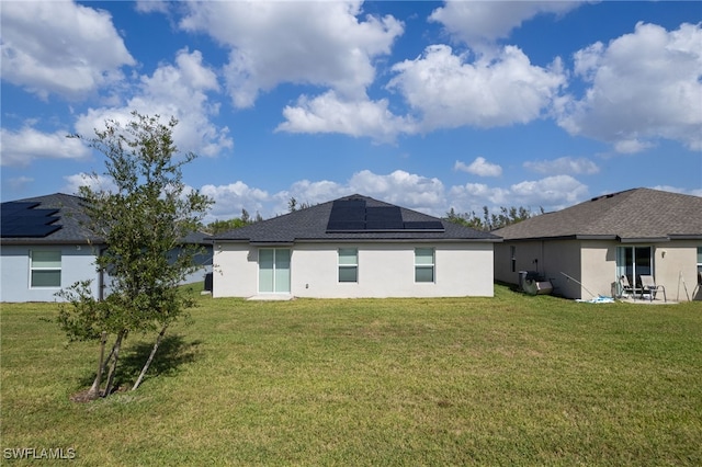 rear view of property with a lawn and solar panels