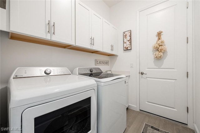 washroom with light wood-type flooring, cabinets, and washing machine and clothes dryer