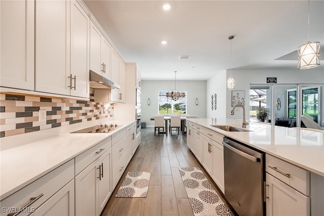 kitchen with under cabinet range hood, a sink, light countertops, appliances with stainless steel finishes, and pendant lighting