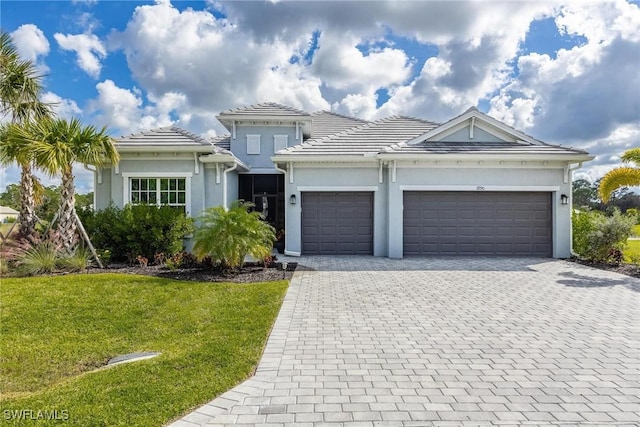 view of front facade featuring decorative driveway, stucco siding, an attached garage, a front yard, and a tiled roof