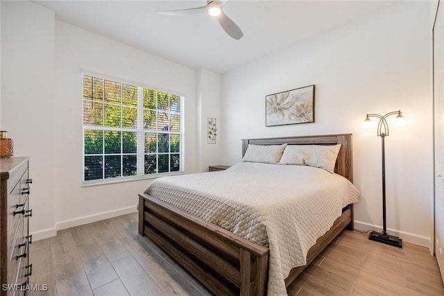 bedroom with light wood-style flooring, baseboards, and ceiling fan