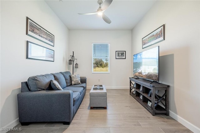 living area with baseboards, a ceiling fan, and wood tiled floor