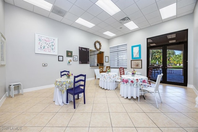 dining area featuring french doors, a paneled ceiling, and light tile patterned flooring