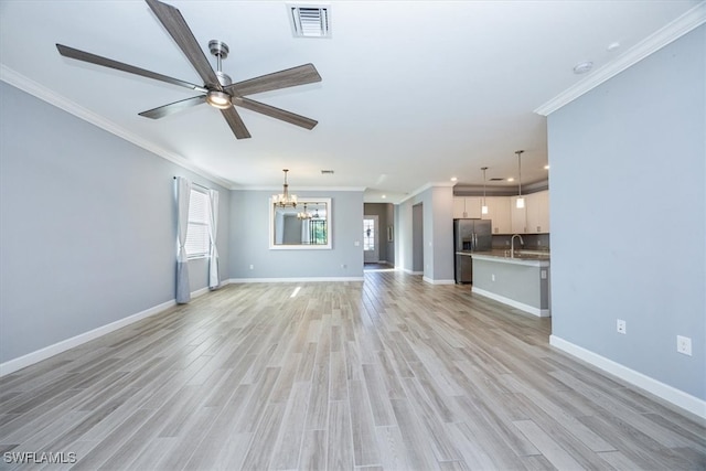 unfurnished living room featuring light hardwood / wood-style floors, crown molding, sink, and ceiling fan with notable chandelier