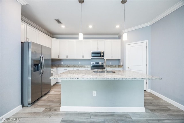 kitchen featuring appliances with stainless steel finishes, decorative light fixtures, a center island with sink, and white cabinets